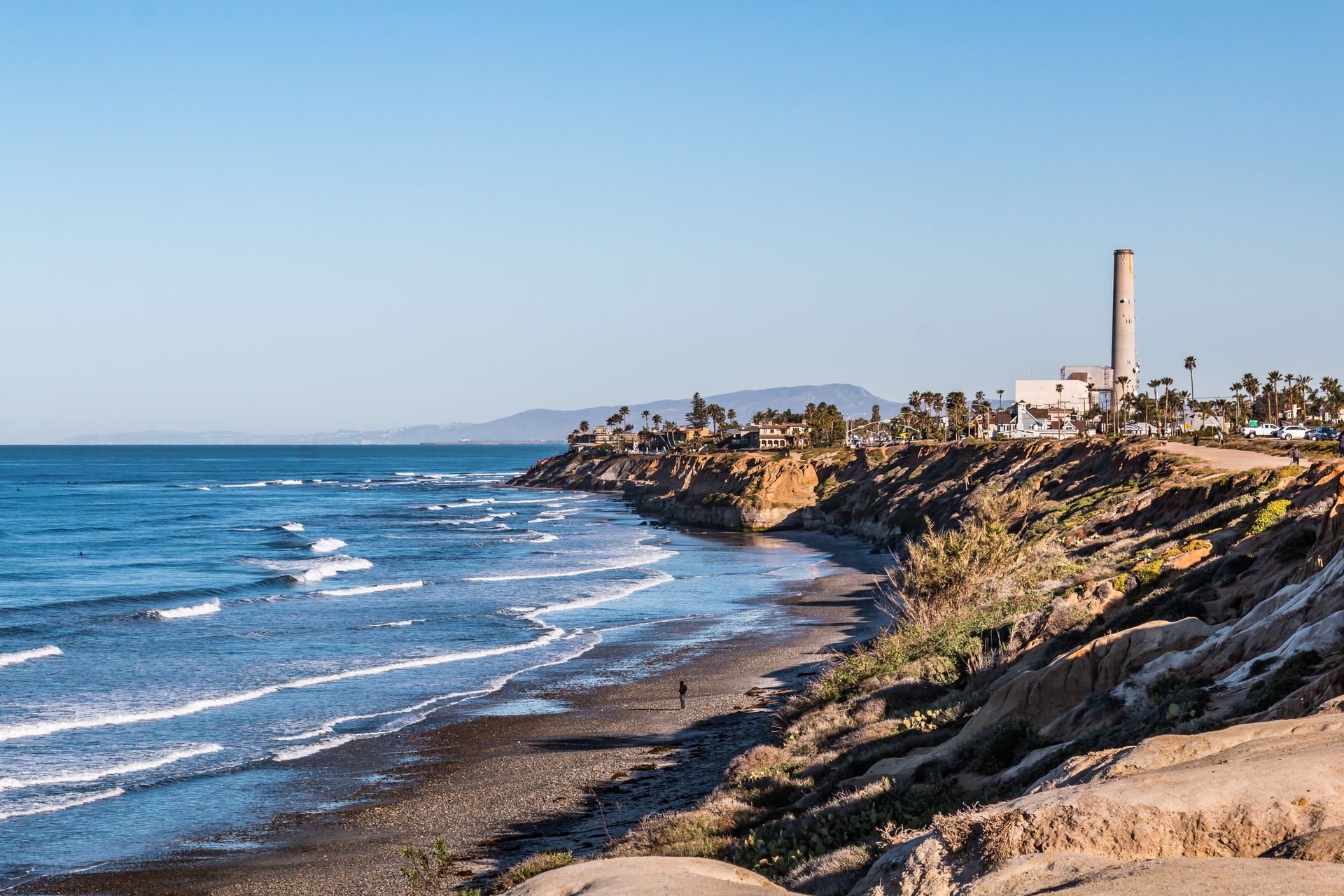 A view of a beach with a lighthouse in the distance.